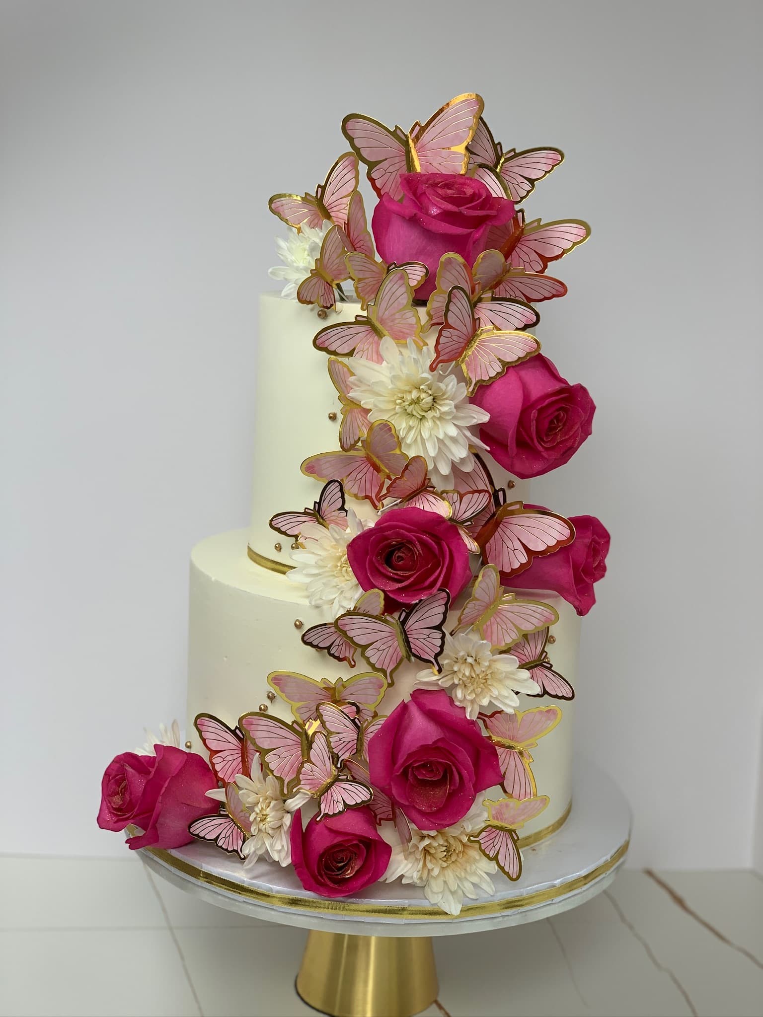 Butterfly and rose two-tier cake with gold accents